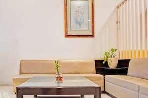 A living room with a sofa, a coffee table, and two potted plants.
