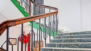 Un escalier avec une main courante en bois et des rampes en métal noir, menant à un palier où se trouve un ballon rouge.