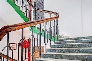 A staircase with a wooden handrail and black metal railings, leading to a landing with a red balloon.