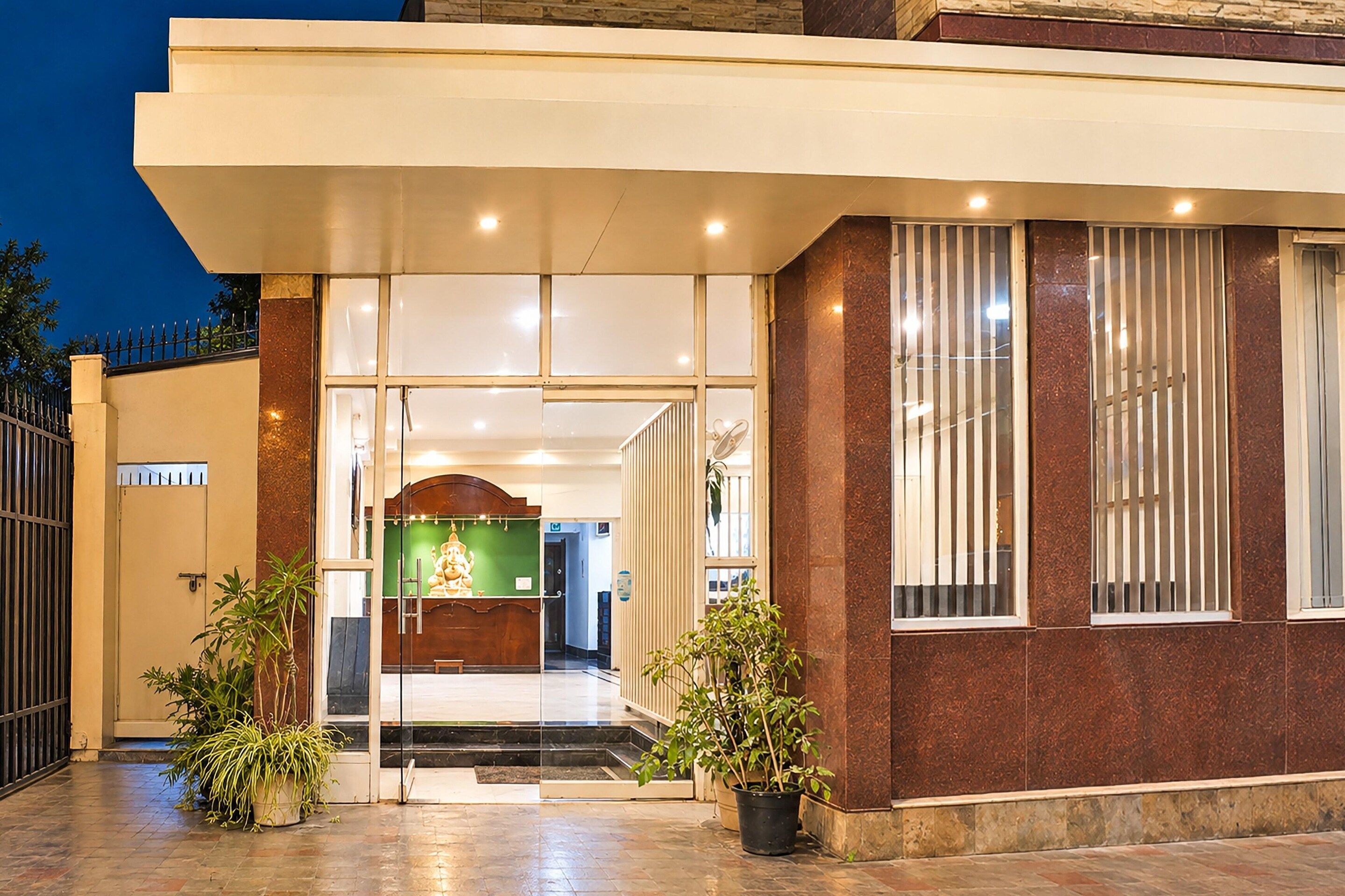 A hotel entrance with a glass door, a reception desk, and a statue.