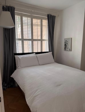 A bedroom with a bed, curtains, a window, and a wall-mounted picture. - Luxury London Apartment  Brand New (London)