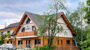 A two-story building with a wooden facade, a balcony, and a visible sign. - Vila DEDO (Vysoké Tatry)