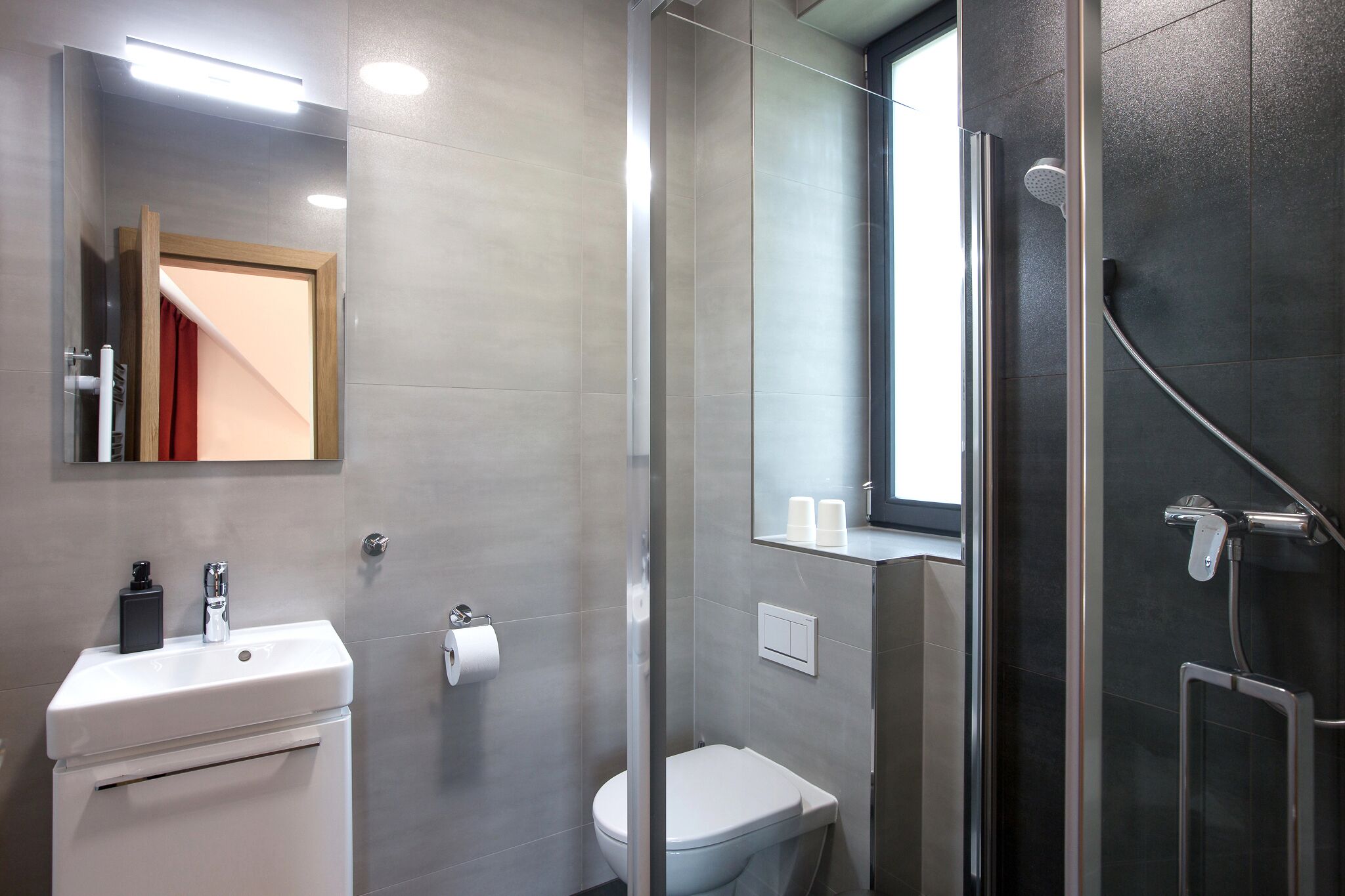 Ein modernes Badezimmer mit einer Glasdusche, einem weißen Waschbecken und einer Toilette.