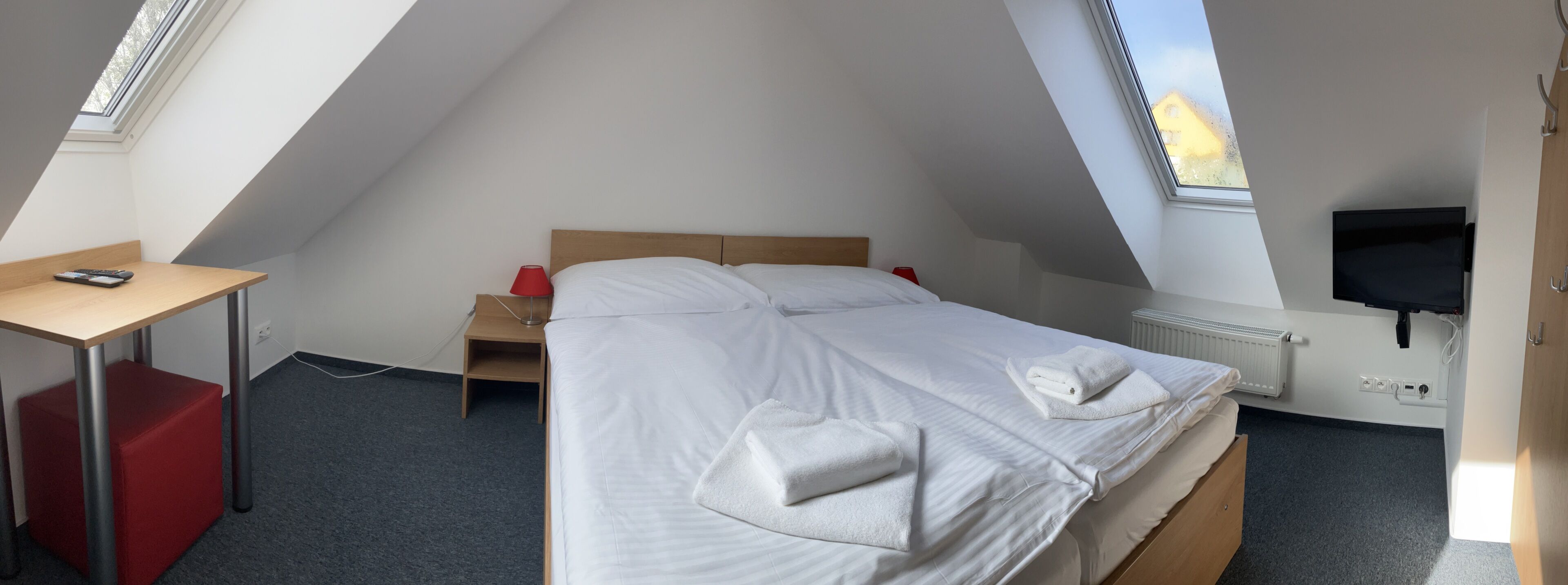 Een kamer met een bed, een bureau, een televisie en een raam.