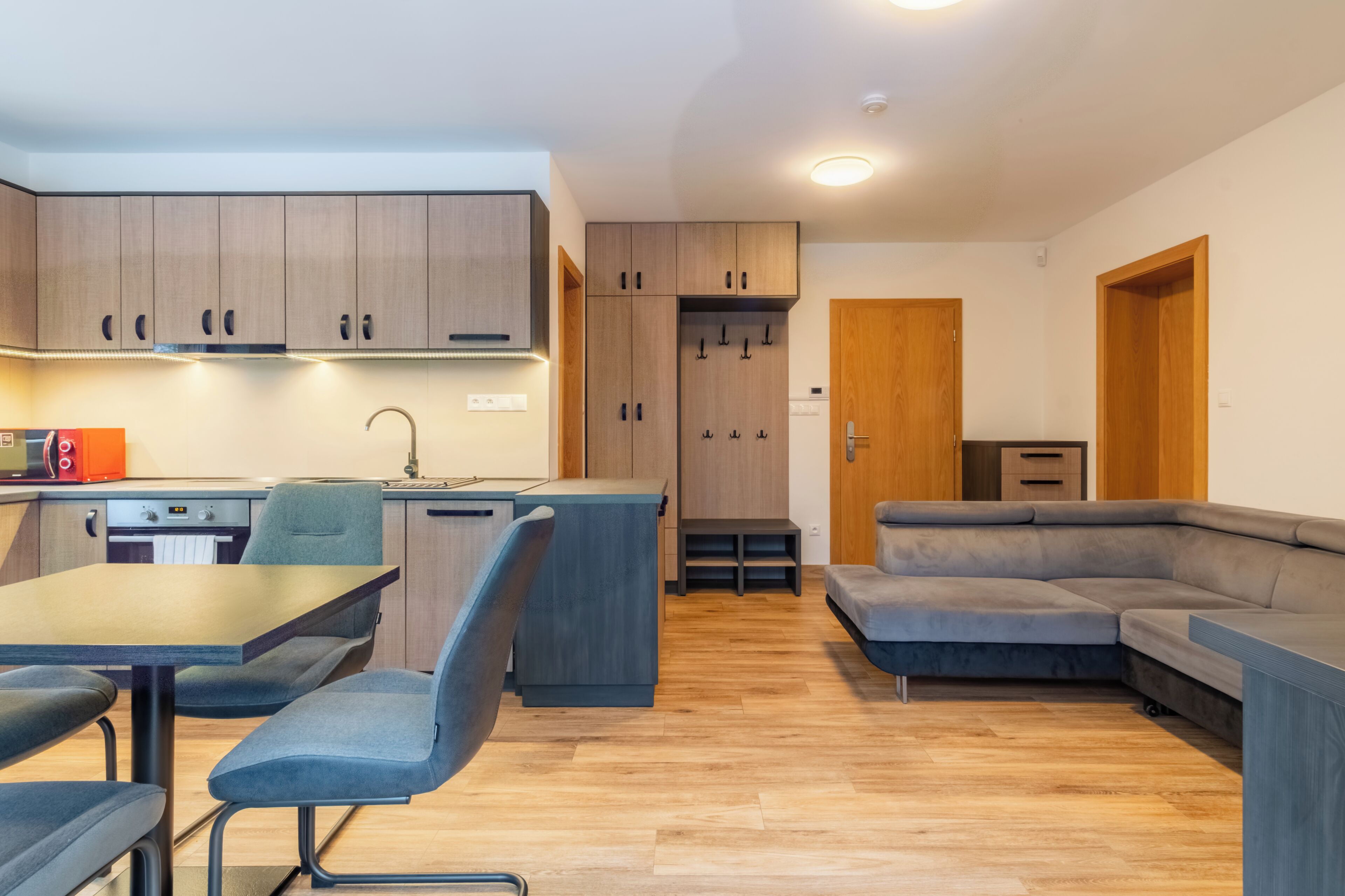Eine moderne Küche mit Holzausstattung, einem Essbereich mit Tisch und Stühlen sowie einer integrierten Couch.