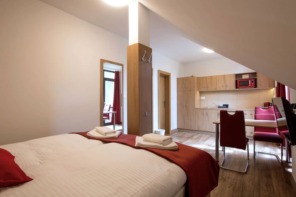 Habitación de hotel con cama, escritorio, silla, microondas y kitchenette.