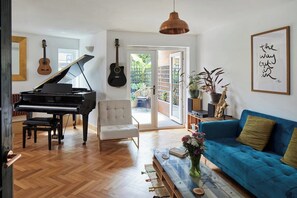 Ein Wohnzimmer mit einem Flügel, einem Sofa, einem Sessel und einem großen Fenster.