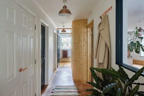 Ein Flur mit einer Holzwand, einem hängenden Mantel und einer Pflanze.