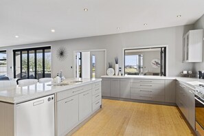 A modern kitchen with a large island, double sinks, and a view to the outdoors.