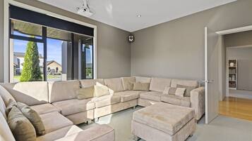 A modern living room with a sectional sofa, a large window, and a door leading to another room.