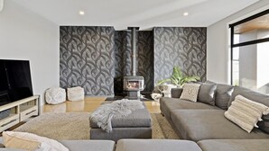 Una sala de estar moderna con un conjunto de sofá, televisor, chimenea y papel tapiz estampado.
