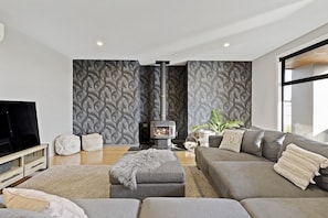 Ein modernes Wohnzimmer mit einer Sofagarnitur, einem Fernseher, einem Kamin und Wandtapete mit Muster.