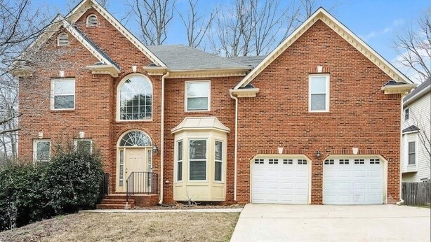A two-story brick house with a central entrance, a bay window, and two attached garages. - Spacious Brick Home in Acworth – Perfect Family Getaway (Acworth)