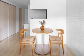 A modern room with a round table, two wooden chairs, a vase with flowers, and a white brick wall. - PREGARE 103 (Sapporoshi)