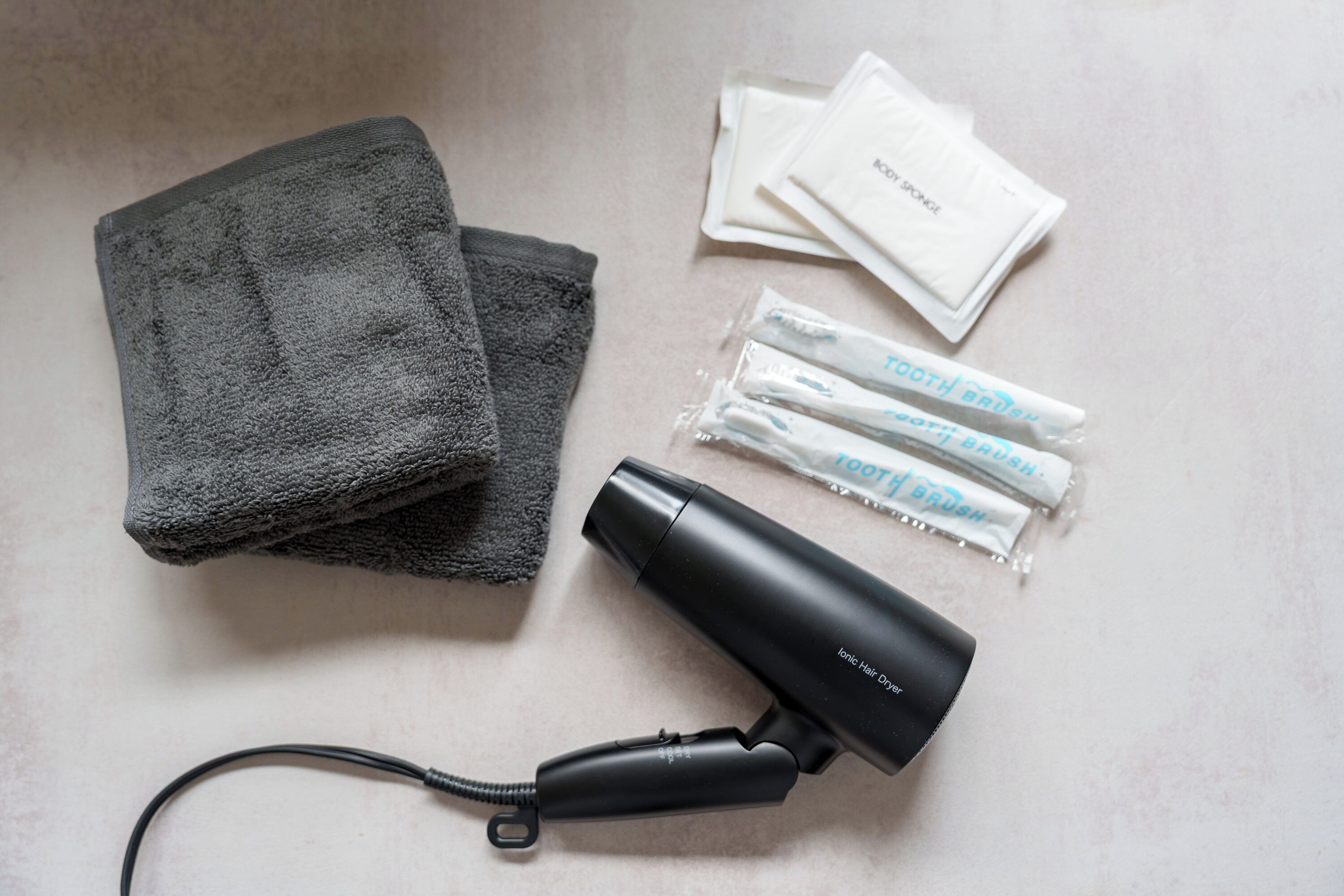 A hair dryer, a towel, and some hair care products on a flat surface.