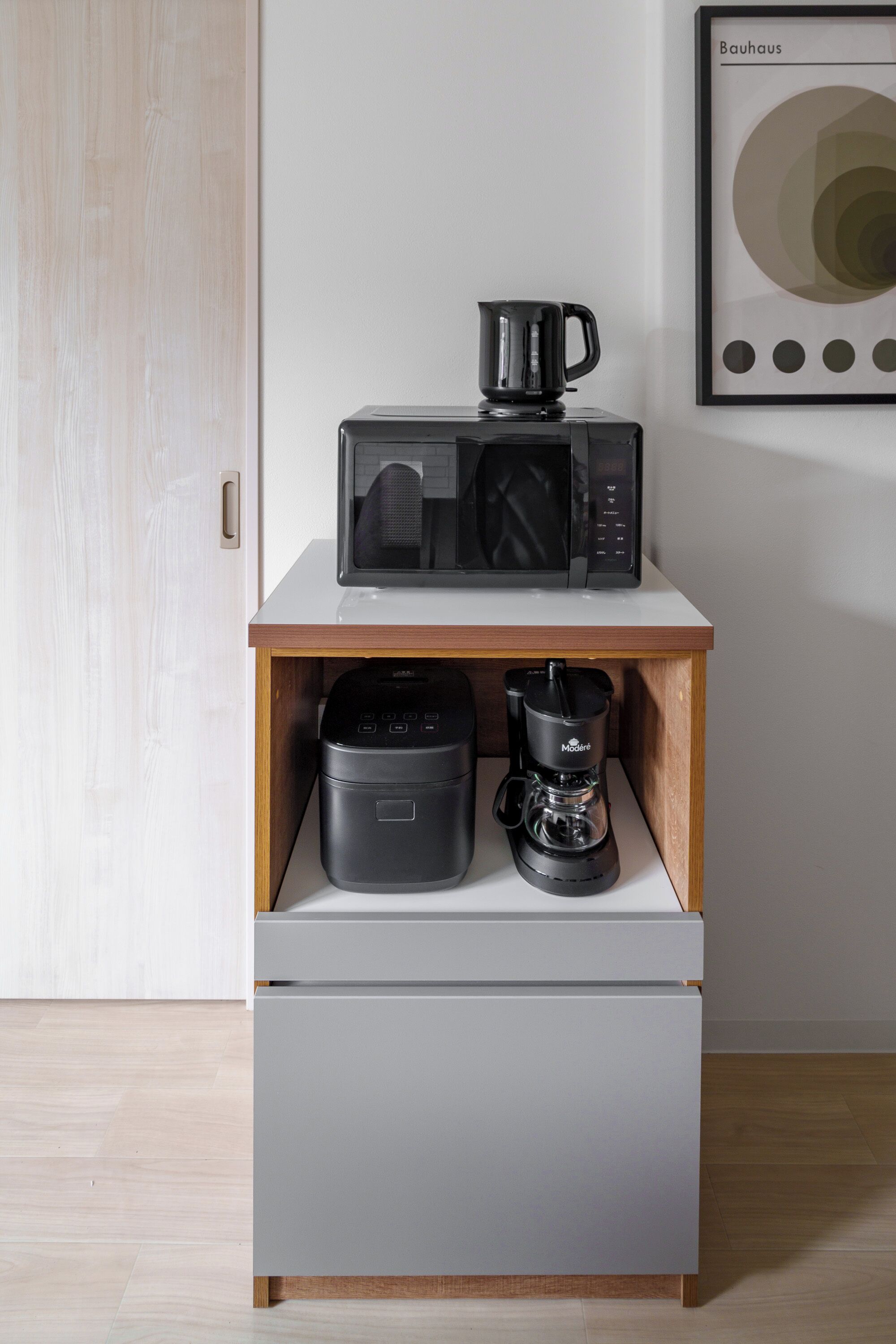A kitchenette with a microwave, coffee maker, and a small oven on a white countertop.