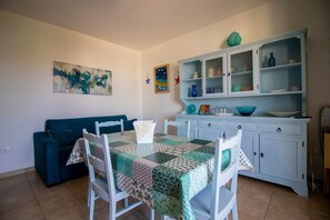 A dining area with a table set for four, a blue sofa, a cabinet with glass doors, and a painting on the wall.