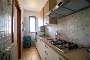 Une cuisine équipée d’une cuisinière à gaz, de meubles de rangement en bois et d’une fenêtre.