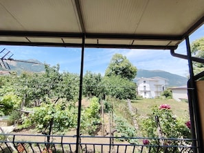 Un balcon offrant une vue sur un vignoble, un bĂątiment blanc et des montagnes en arriĂšre-plan.