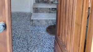 Una escalera con barandilla, una puerta con panel de vidrio esmerilado y un suelo moteado.