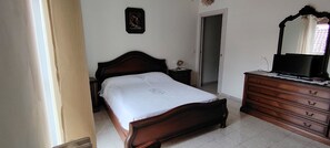 A bedroom with a wooden bed, a dresser, a mirror, and a door.