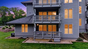 Une maison à deux étages dotée d’un balcon, de grandes fenêtres et d’une pelouse bien entretenue.
