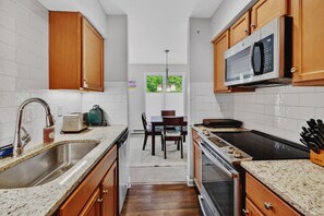 Une cuisine avec des meubles en bois, un évier en acier inoxydable, un four à micro-ondes, un grille-pain et une cuisinière.