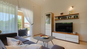 Ett vardagsrum med en soffa, ett soffbord, en tv och en matplats med ett bord och stolar.