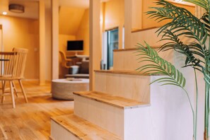 A modern interior with wooden steps, a dining area, and a plant.