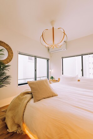 A hotel room with a bed, a large window, a wall-mounted air conditioner, and a hanging light fixture. - Hidden Playground Kagurazaka 3BR (Shinjuku City)