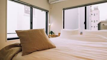 A hotel room with a bed, a window, and an air conditioning unit.