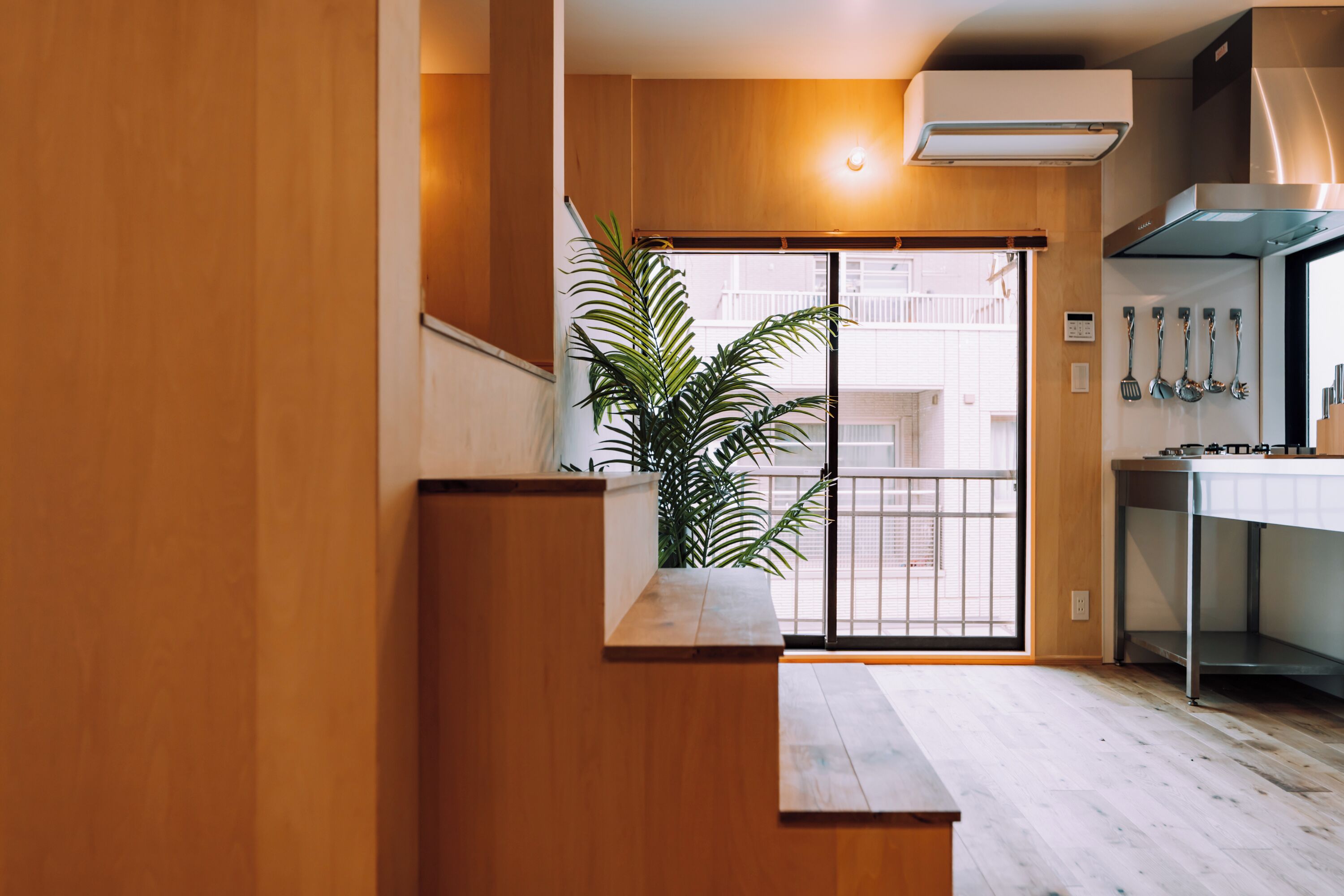 A modern kitchen with wooden cabinetry, a built-in stove, and a potted plant.