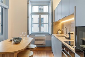Eine moderne Küche mit Holztisch, integrierten Geräten und einem großen Fenster.