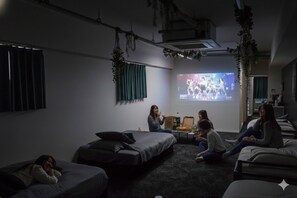 Una habitación con cama, sofá, televisor y proyector.