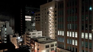 Vista nocturna de un paisaje urbano con edificios modernos, incluyendo un edificio destacado con una fachada singular y numerosas ventanas.
