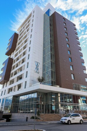 A multi-story hotel with a prominent logo on the facade, large glass windows, and a modern architectural design. - Status M Apartments WOW (Budva)