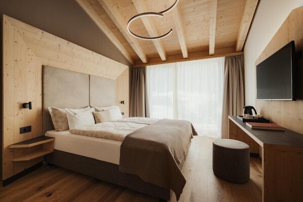 Un dormitorio moderno con techo de madera, una cama grande, un escritorio y un televisor.