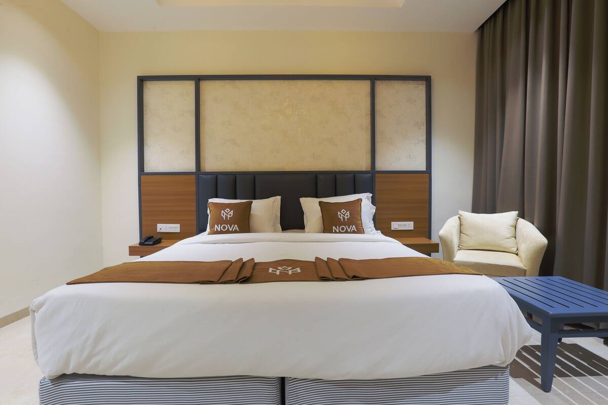 Habitación de hotel con una cama grande, dos mesitas de noche, una silla y una pequeña mesa.