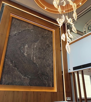 A room with a large dark marble wall, wooden paneling, and a modern chandelier. - Hotel Nova Platinum Ujjain (Ujjain)