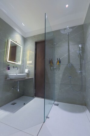 A modern bathroom with a glass-enclosed shower, a sink with a mirror, and two bottles of soap on the wall. - Hotel Nova Platinum Ujjain (Ujjain)