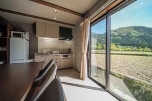 Una cocina moderna con electrodomésticos integrados, un comedor y un amplio ventanal corredera con vistas panorámicas al exterior.