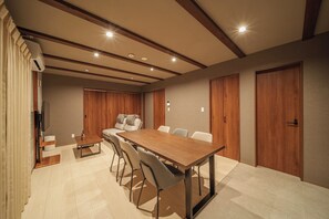Una sala de conferencias moderna con una mesa de madera, sillas, un sofá y armarios empotrados de madera.