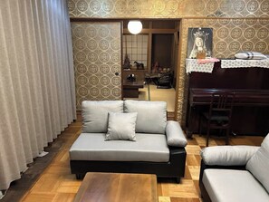 A living room with a sofa, a coffee table, and a piano.