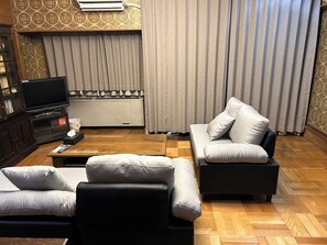 En stue med sofa, fjernsyn og skab.