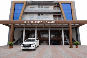 A modern building with a sign reading 'THE ROYAL AWADH' and a white car parked in front.