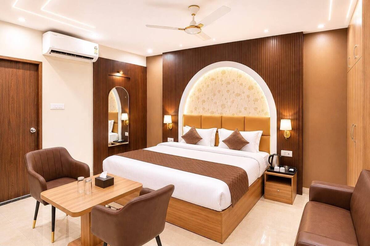 A hotel room with a bed, two chairs, a table, a nightstand, and a ceiling fan.