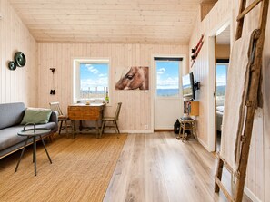 Una habitación acogedora con suelo de madera, un sofá, una mesa de comedor y un cuadro de un rostro equino.