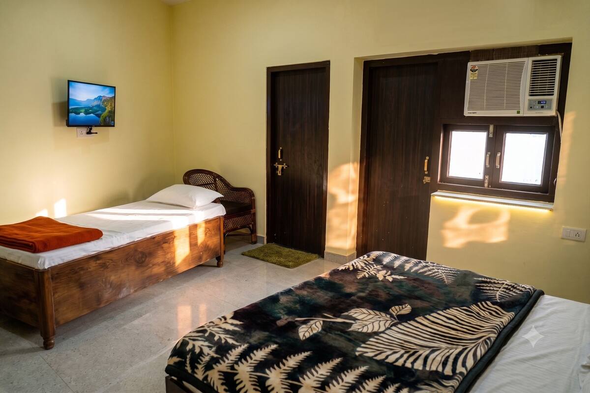 Un dormitorio con dos camas, televisión, armario y aire acondicionado.