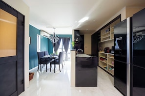 Eine moderne Küche mit Kühlschrank, ein Essbereich mit Stühlen und Tisch, und ein Flur, der zu einem Zimmer mit Fenster führt.