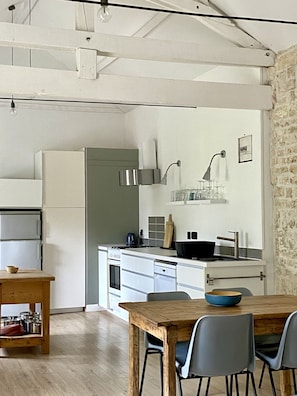 Uma cozinha moderna com armários brancos, uma mesa de madeira e duas cadeiras.
